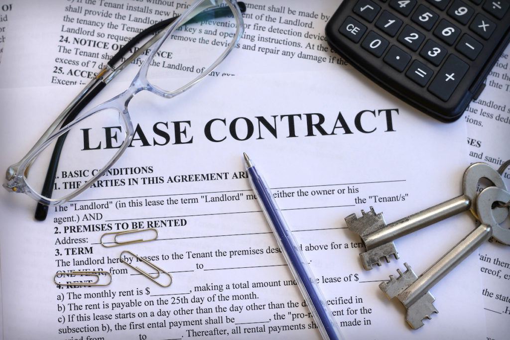 lease contract with glasses, keys, calculator on top of desk
